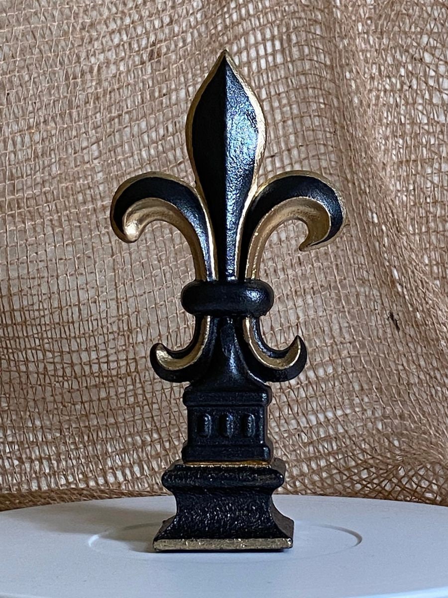 5 1/2” and 7 1/4” high cast iron Fleur de lis on pedestal. Beautifully hand painted with metallic gold accents