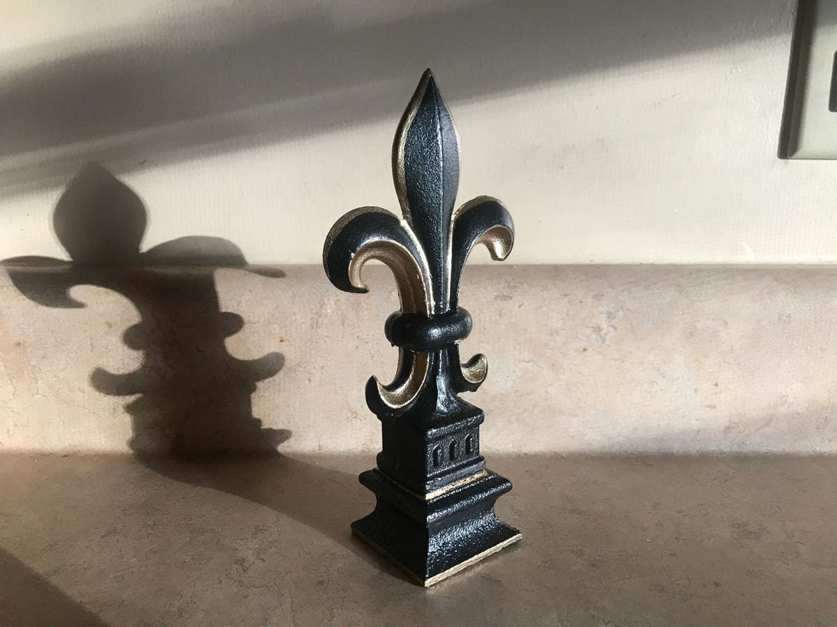 5 1/2” and 7 1/4” high cast iron Fleur de lis on pedestal. Beautifully hand painted with metallic gold accents