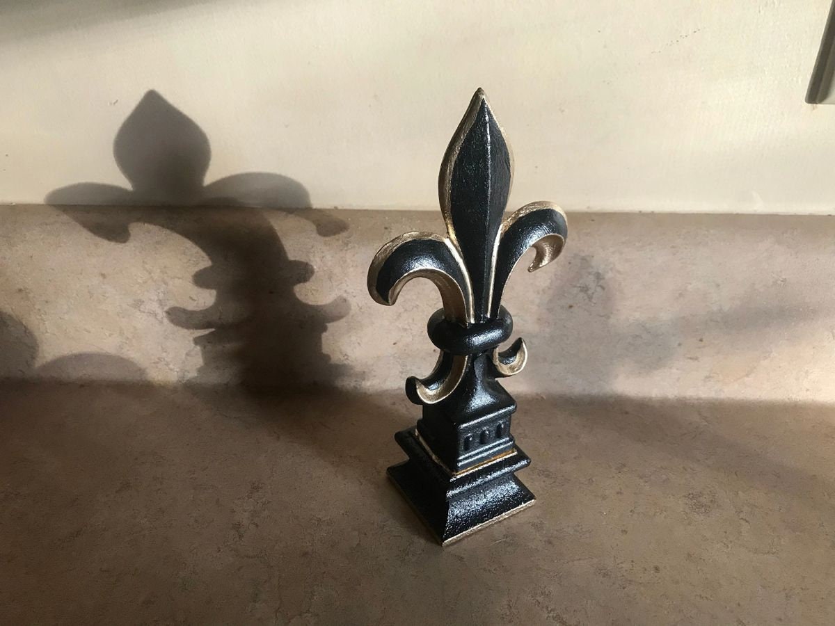 5 1/2” and 7 1/4” high cast iron Fleur de lis on pedestal. Beautifully hand painted with metallic gold accents